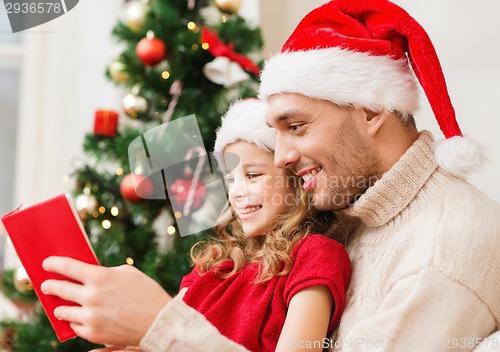 Image of smiling father and daughter reading book