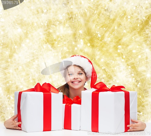Image of smiling girl in santa helper hat with gift boxes