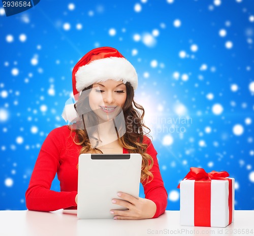 Image of smiling woman in santa hat with gift and tablet pc