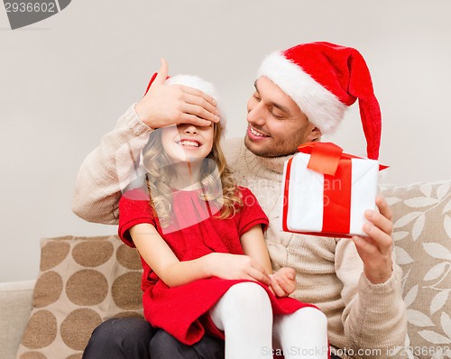 Image of smiling father surprises daughter with gift box