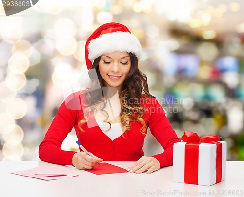 Image of smiling woman with gift box writing letter