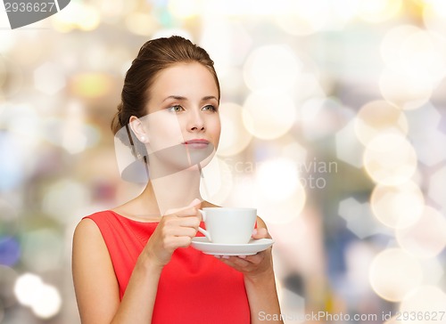 Image of smiling woman in red dress with cup of coffee