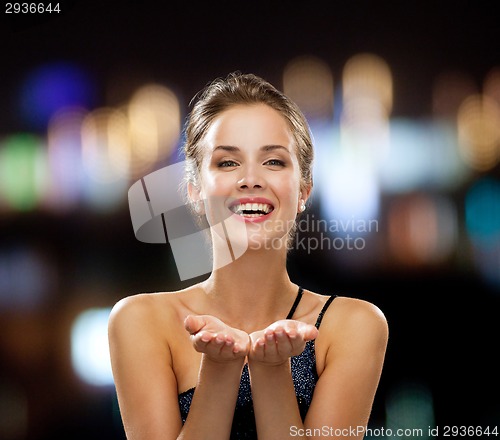 Image of laughing woman in evening dress holding something