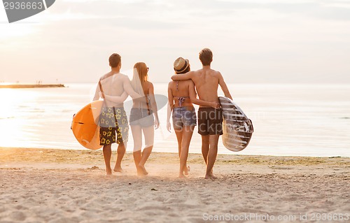 Image of smiling friends in sunglasses with surfs on beach