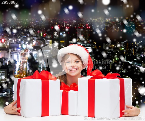 Image of smiling girl in santa helper hat with gift boxes