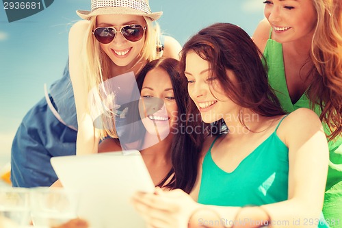 Image of smiling girls looking at tablet pc in cafe