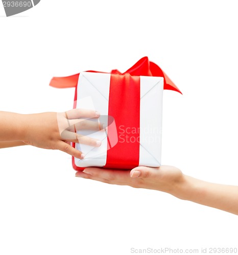 Image of close up of child and mother hands with gift box