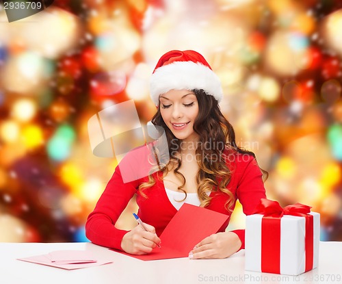 Image of smiling woman with gift box writing letter