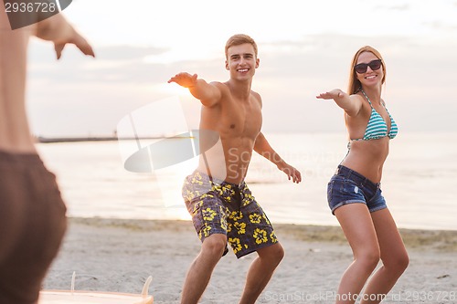 Image of smiling friends in sunglasses with surfs on beach