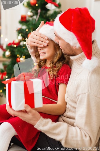 Image of smiling father surprises daughter with gift box