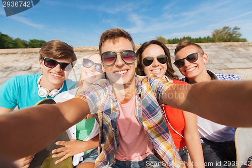 Image of group of smiling friends making selfie outdoors