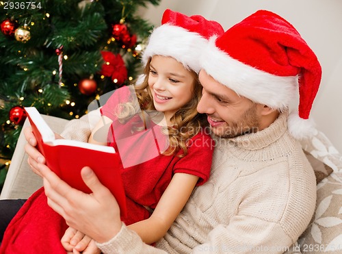 Image of smiling father and daughter reading book