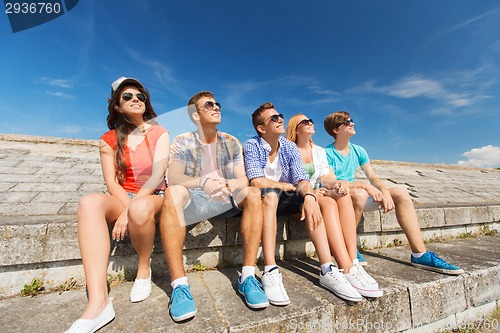 Image of group of smiling friends sitting on city street