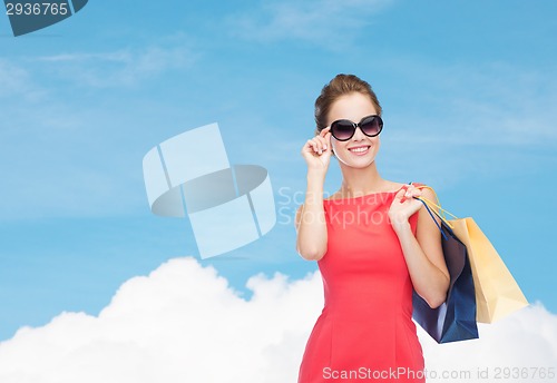 Image of smiling elegant woman in dress with shopping bags