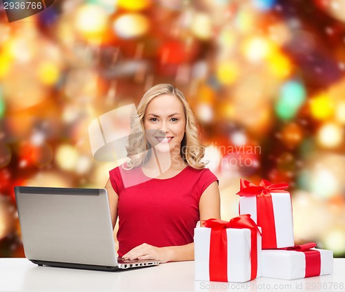 Image of smiling woman in red shirt with gifts and laptop