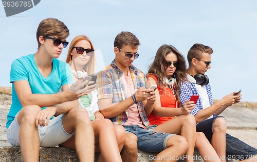 Image of group of friends with smartphones outdoors