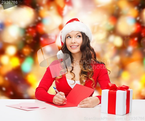 Image of smiling woman with gift box writing letter