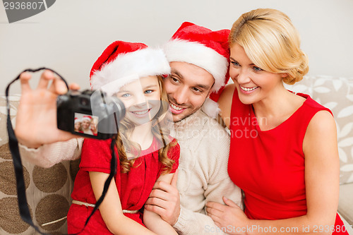 Image of smiling family in santa helper hats taking picture