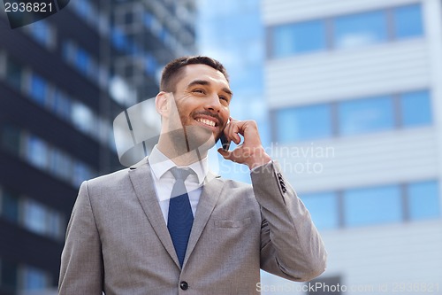 Image of smiling businessman with smartphone outdoors