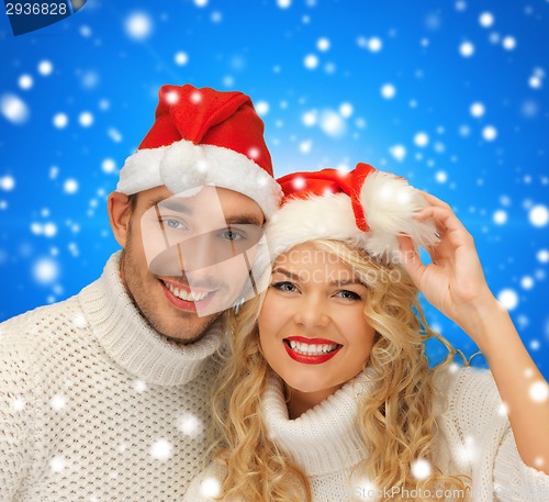 Image of smiling couple in sweaters and santa helper hats