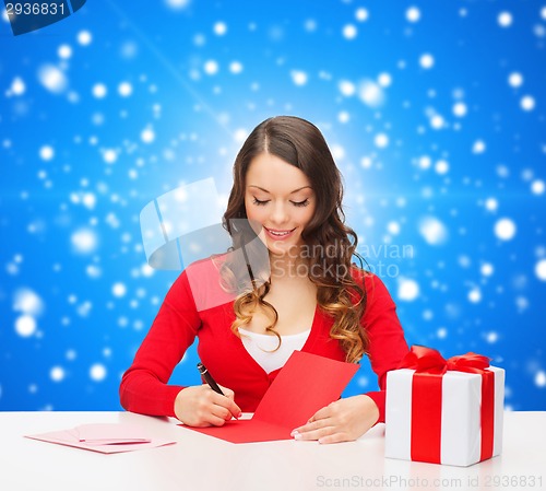 Image of smiling woman with gift box writing letter