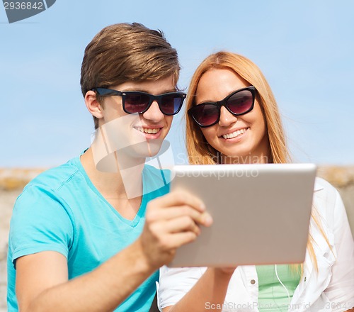 Image of group of smiling friends with tablet pc outdoors