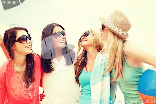 Image of smiling girls with ball and towel on the beach