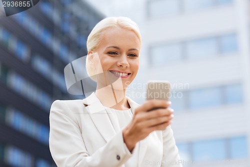 Image of smiling businesswoman with smartphone outdoors