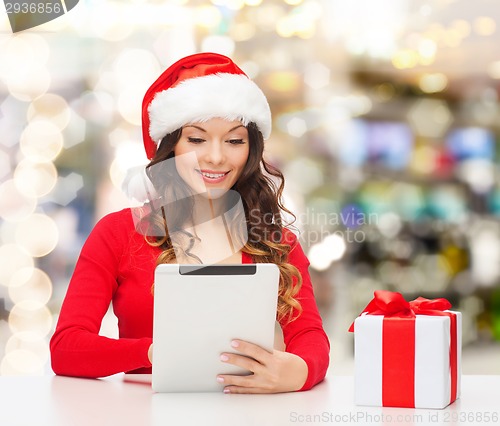Image of smiling woman in santa hat with gift and tablet pc