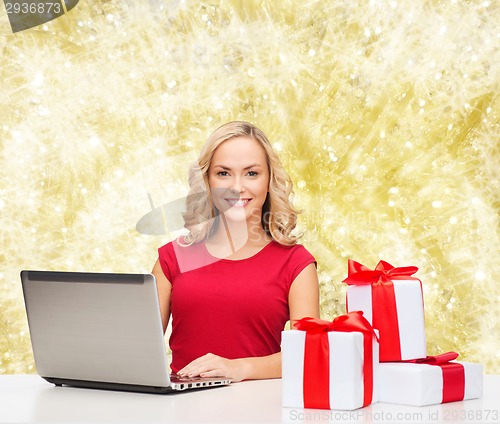 Image of smiling woman in red shirt with gifts and laptop