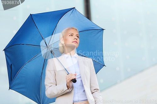 Image of young serious businesswoman with umbrella outdoors