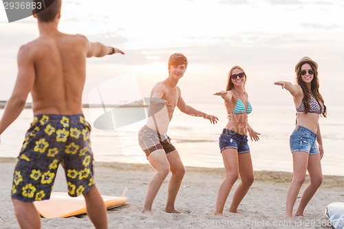 Image of smiling friends in sunglasses with surfs on beach