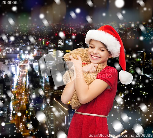 Image of smiling girl in santa helper hat with teddy bear