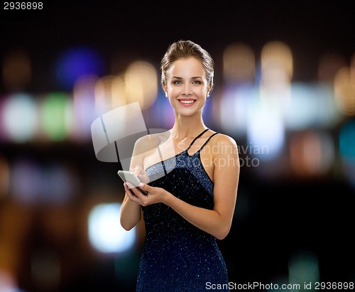 Image of smiling woman in evening dress with smartphone