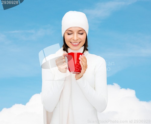 Image of smiling young woman in winter clothes with cup