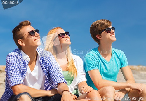 Image of group of smiling friends sitting on city street