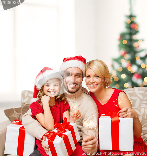 Image of smiling family holding gift boxes and sparkles