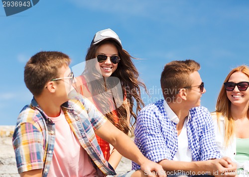 Image of group of smiling friends sitting on city street