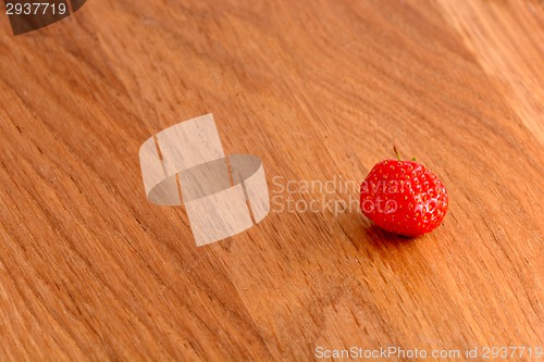 Image of close up of small strawberry on wood