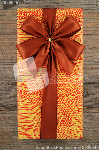Image of beautifully decorated gift box with bow on wooden