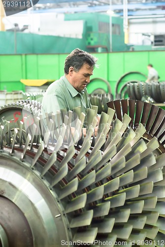 Image of Mechanic works with part of aviation engine