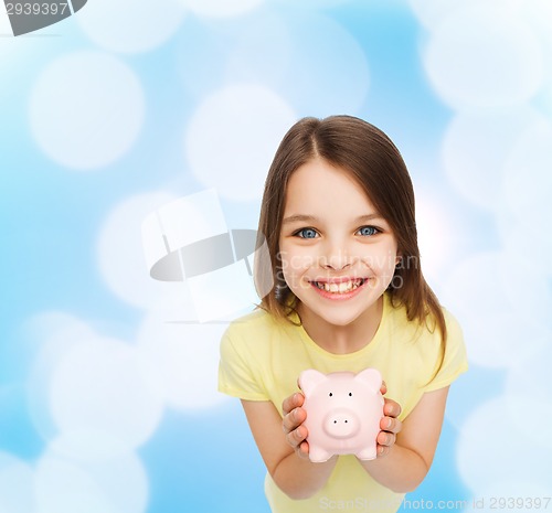 Image of beautiful little girl with piggy bank