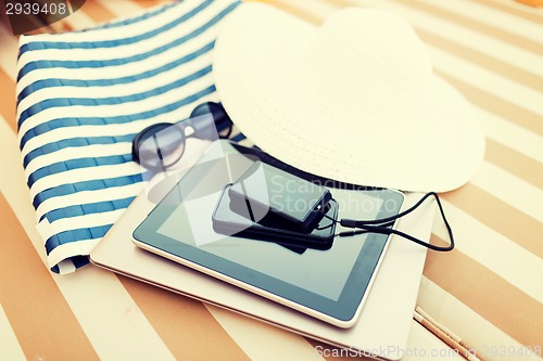Image of close up of tablet pc and smartphone on beach