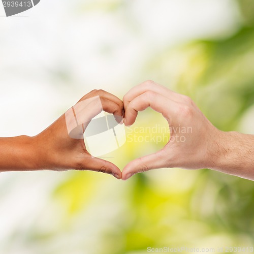 Image of woman and man hands showing heart shape