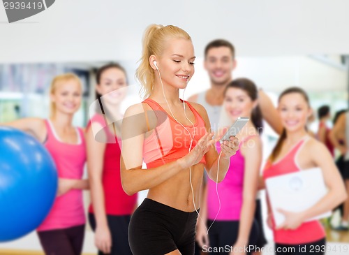 Image of smiling sporty woman with smartphone and earphones