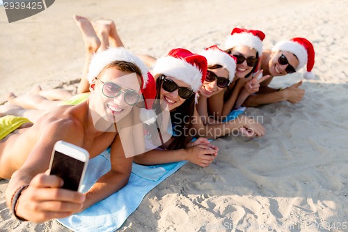 Image of group of friends in santa hats with smartphone