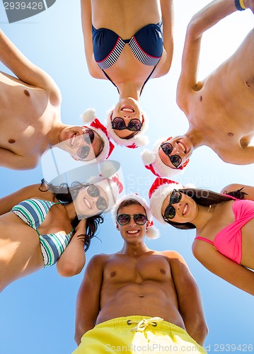 Image of smiling friends in circle on summer beach