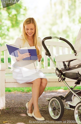 Image of happy mother with book and stroller in park