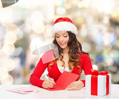 Image of smiling woman with gift box writing letter