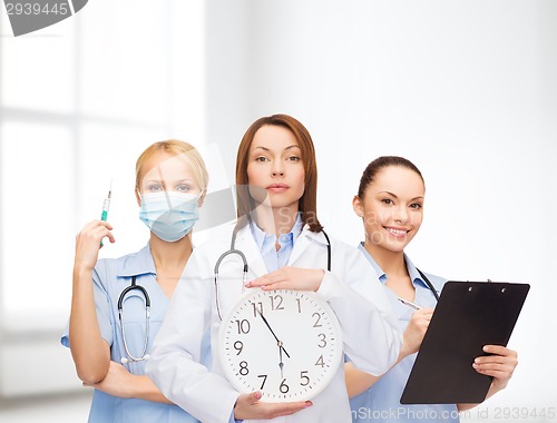 Image of calm female doctor and nurses with wall clock